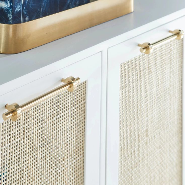 a close up of a gold frame on a white cabinet with blue and white wallpaper