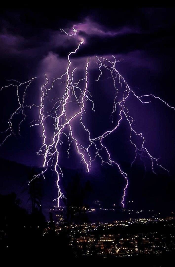 lightning strikes in the night sky over a city