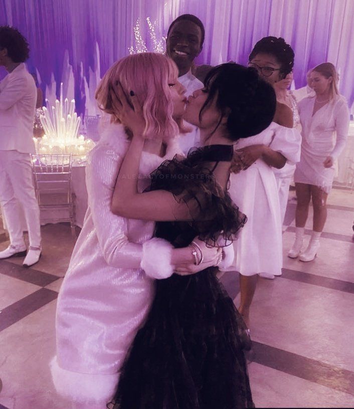 two women in white dresses are hugging each other on the dance floor at a wedding