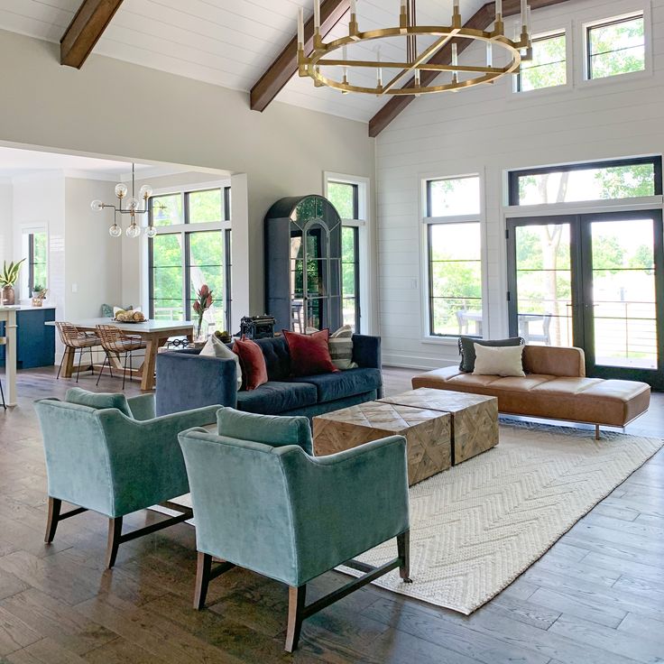 a living room filled with lots of furniture next to tall windows and wooden beams on the ceiling