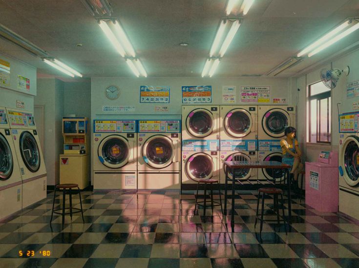 an empty laundry room with washers and dryers on the walls, in front of a checkered floor