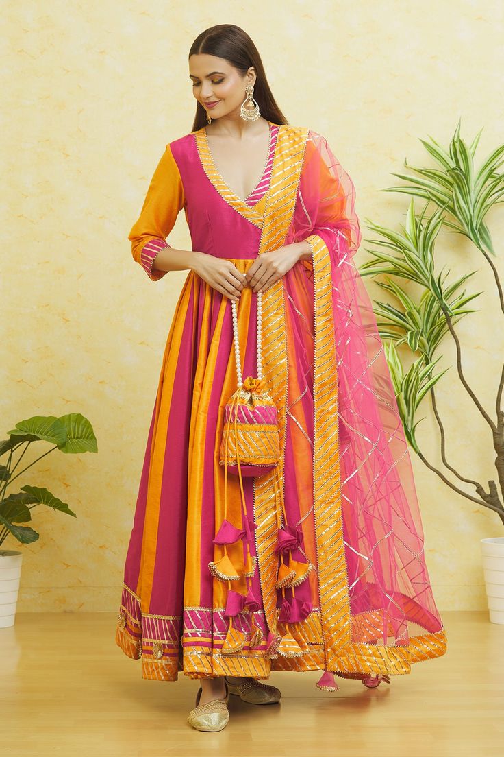 Yellow and pink angarkha style panelled anarkali with gota embroidered neckline, sleeves and hem. Paired with a pink pant, dupatta and a potli bag.
Components: 4
Pattern: Embroidered
Type Of Work: Gota
Neckline: V Neck
Sleeve Type: Three-quarter
Fabric: Cotton Silk
Color: Yellow,Pink
Other Details: 
Side tassles
Closure: 
Pant: Front drawstring tie-up
Occasion: Mehendi and Haldi - Aza Fashions Colorful Anarkali Dress, Side Latkan Design For Kurti, Angarkha Anarkali Indian Fashion, Yellow And Pink Anarkali, Dholki Dress, Mehendi Outfit Ideas, Bandhani Dresses, Gulabo Jaipur, Mayon Dresses