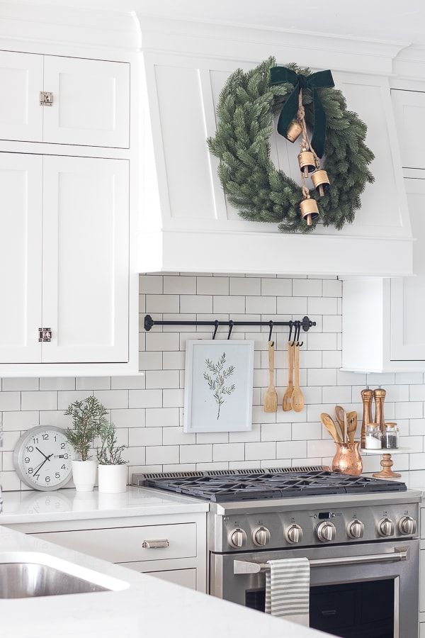 a kitchen with white cabinets and a wreath hanging on the wall above the stove top