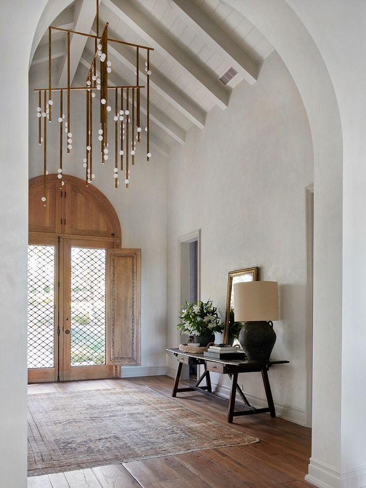 a room with a chandelier hanging from it's ceiling and wooden floors