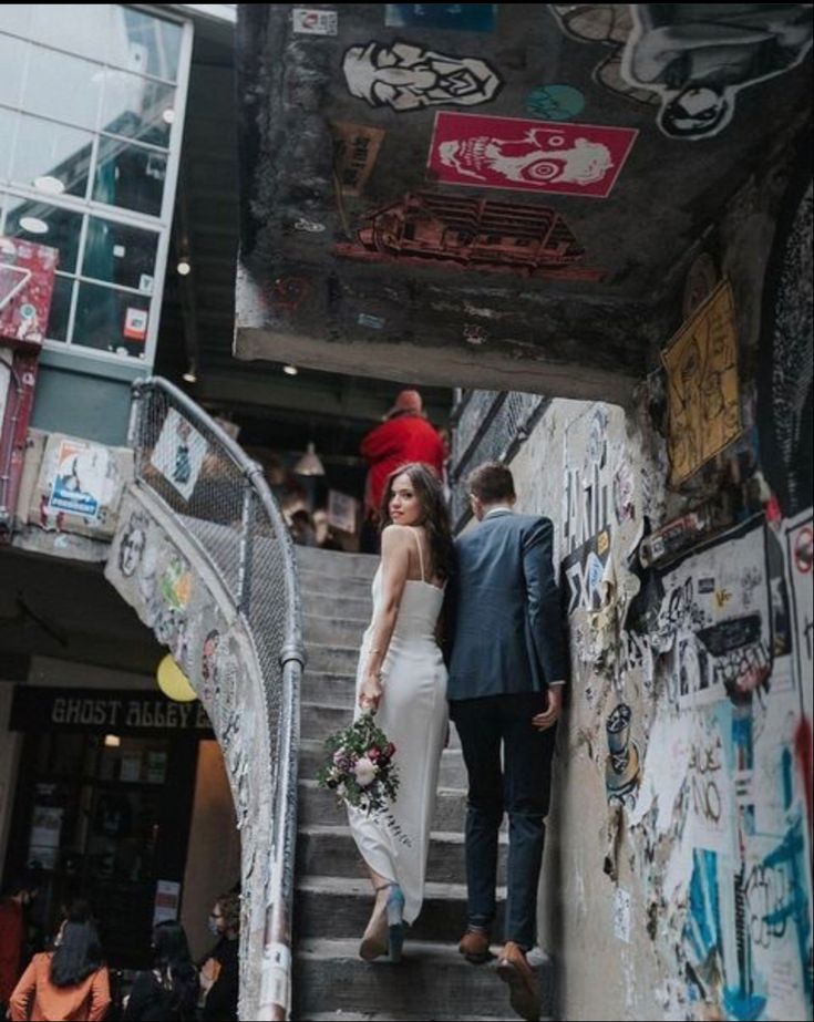 a bride and groom walking down the stairs at their wedding reception in an alleyway