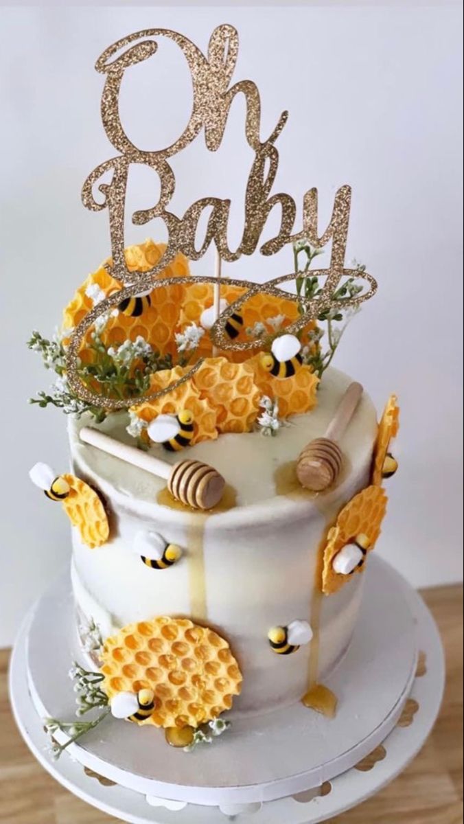 a cake decorated with honeycombs, bees and the word oh baby on top