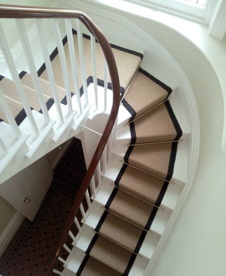 a spiral staircase with carpeted steps leading up to a window