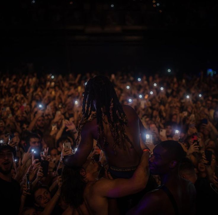 a man is hugging his girlfriend in the middle of a crowd with their cell phones