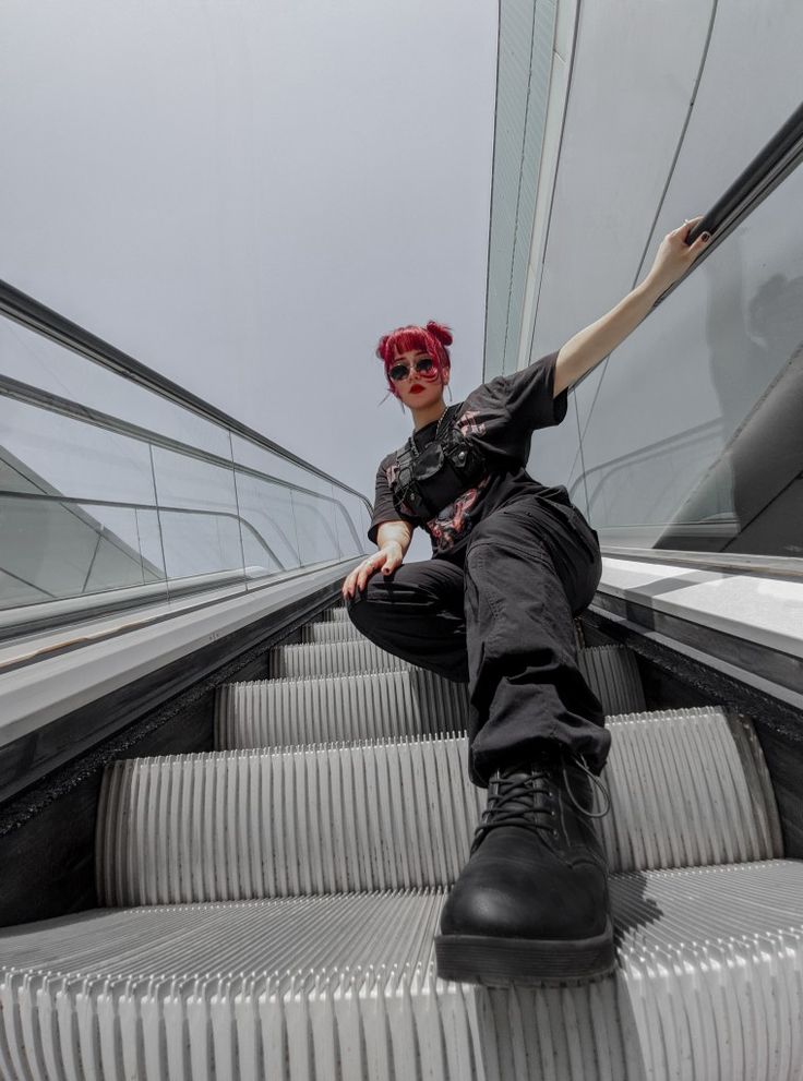 a woman with red hair is sitting on an escalator and posing for the camera