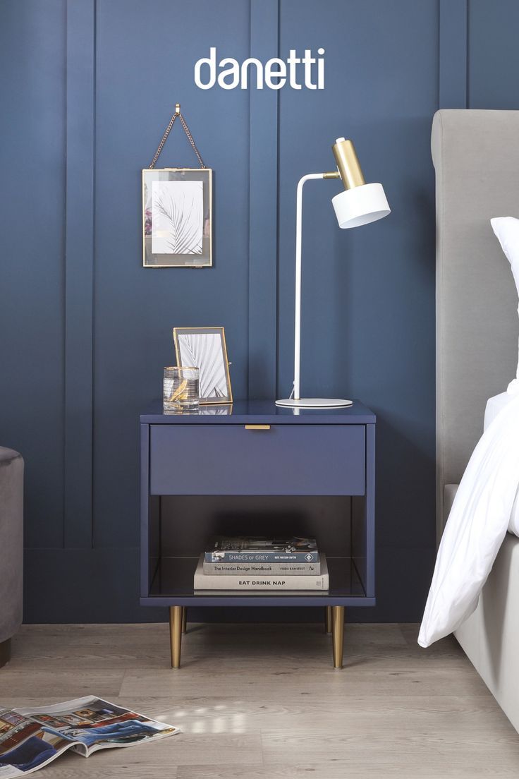 a bedroom with blue walls and white bedding, two pictures on the wall next to a night stand