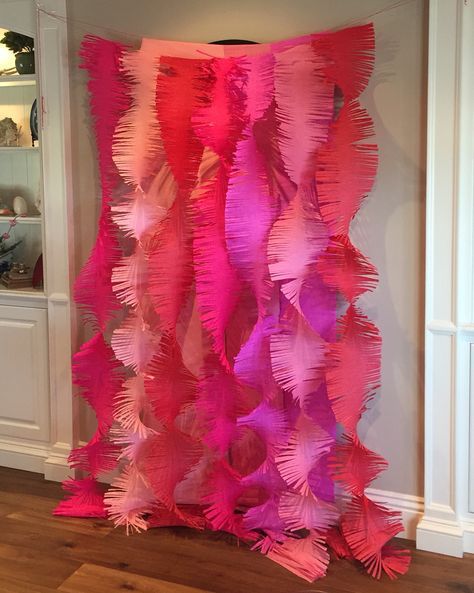 pink and red streamers hanging from the ceiling in a room with wooden floors, white walls