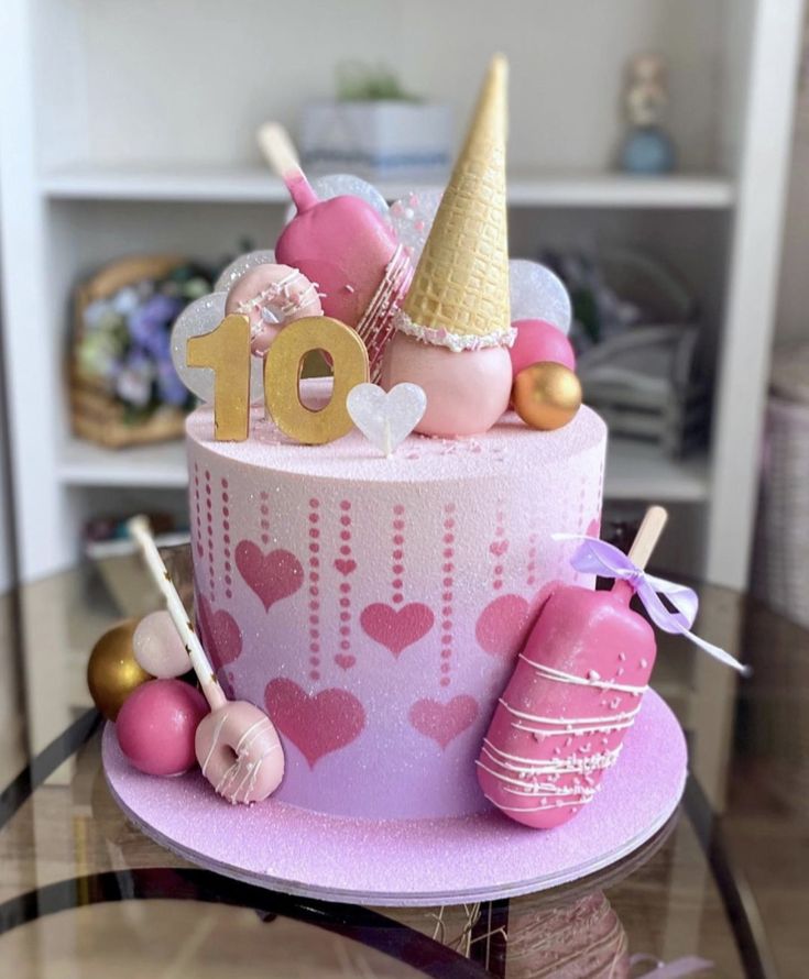 a pink birthday cake sitting on top of a table