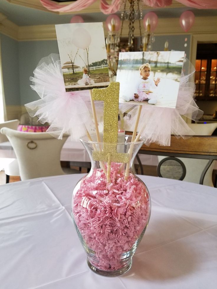 a vase filled with pink and white flowers sitting on top of a table next to a chandelier