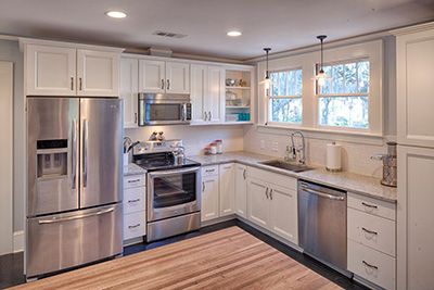 an empty kitchen with stainless steel appliances and white cabinets, wood counter tops, and hardwood flooring