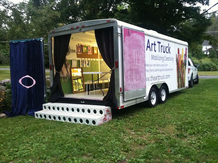 an art truck parked in the grass with its door open and curtains pulled up to it's sides