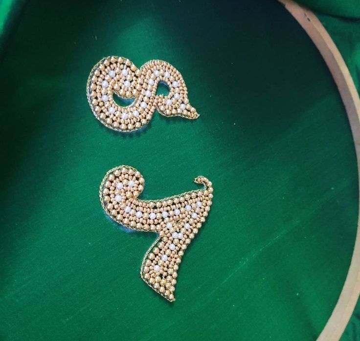 two brooches are sitting on a green cloth