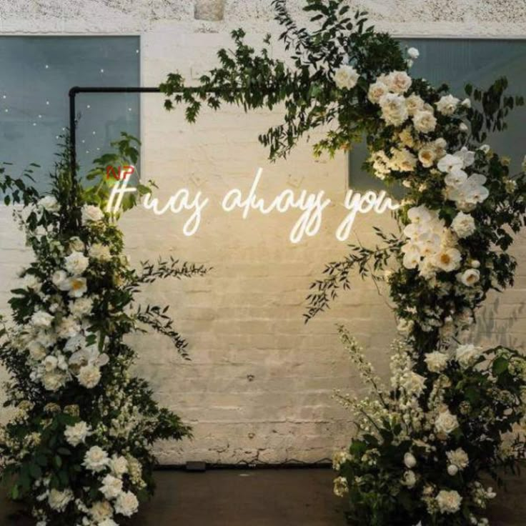 two white flowers and greenery are on display in front of a sign that says,'may always you '