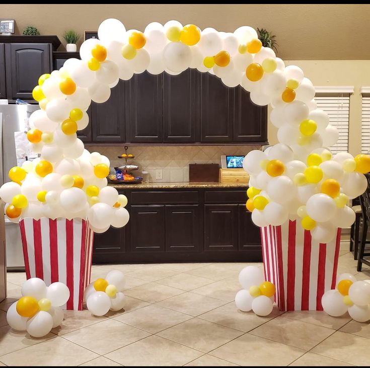 two popcorn buckets with balloons on them in front of a kitchen counter and refrigerator