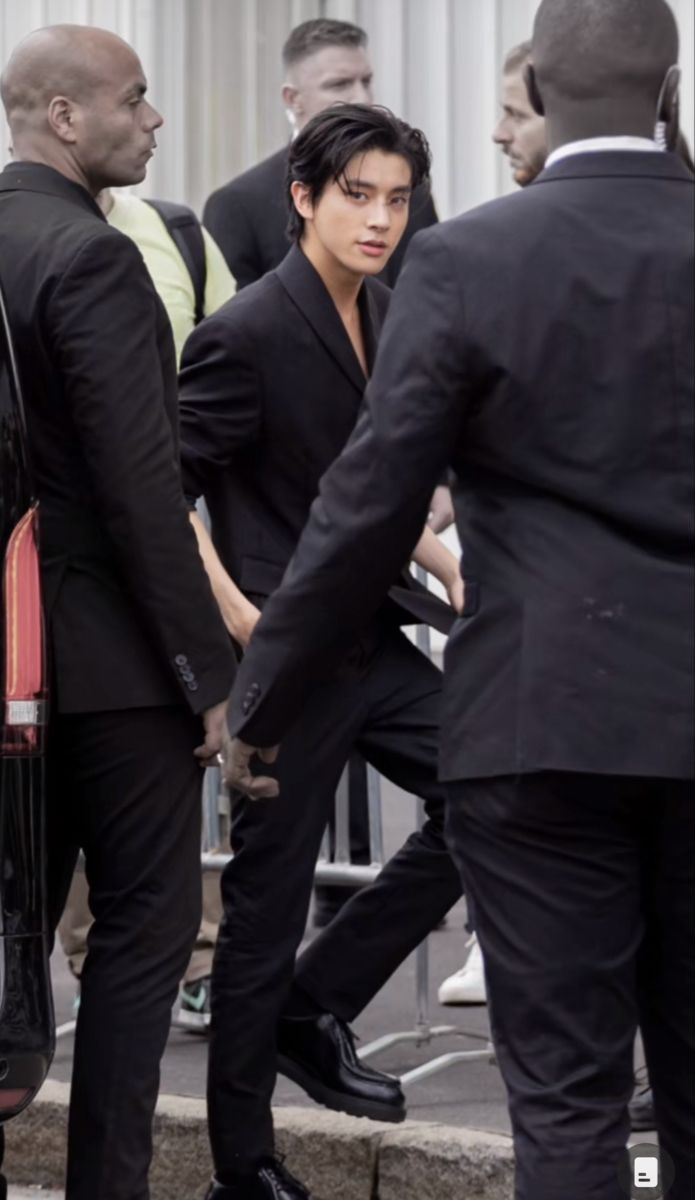 two men in suits are shaking hands with one another as others look on from behind them