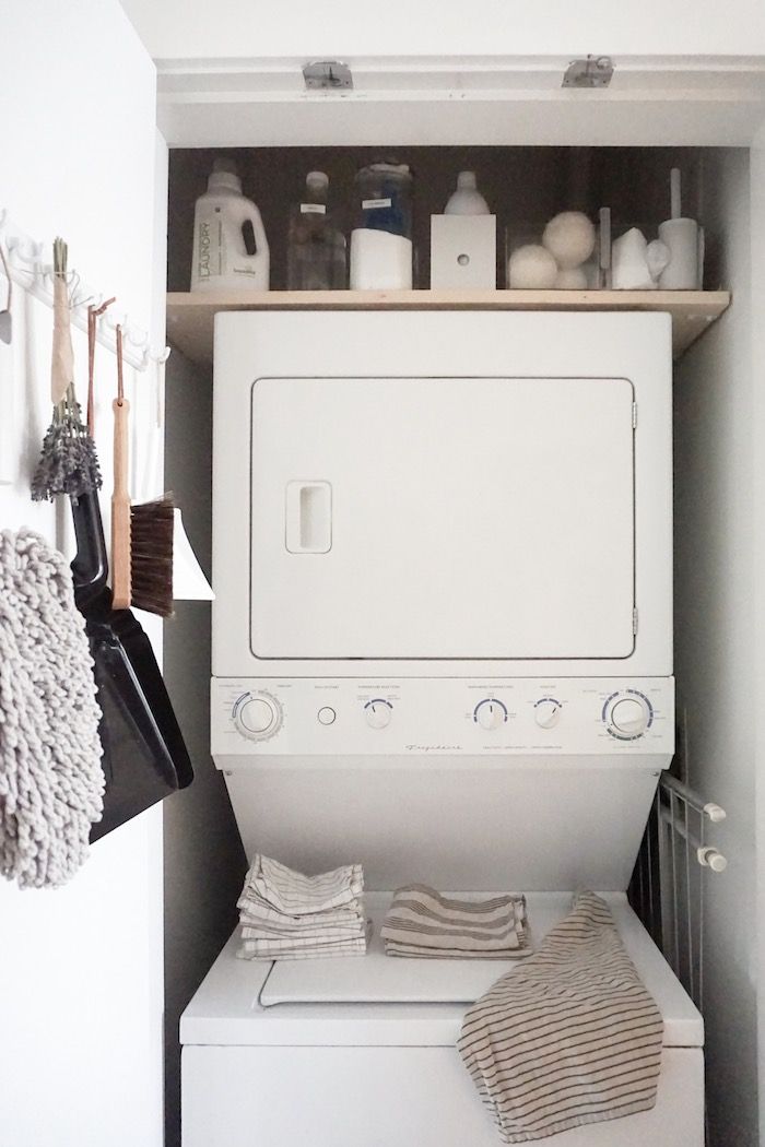 a white washer sitting inside of a dryer next to a shelf filled with cleaning supplies