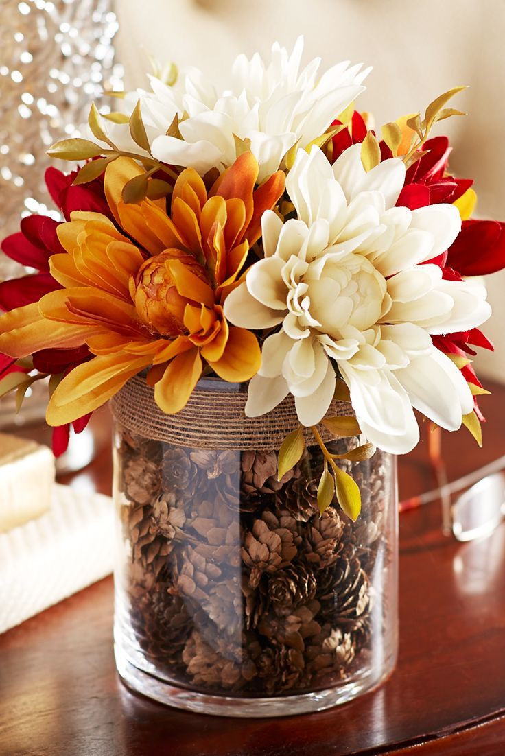 a vase filled with lots of flowers on top of a table