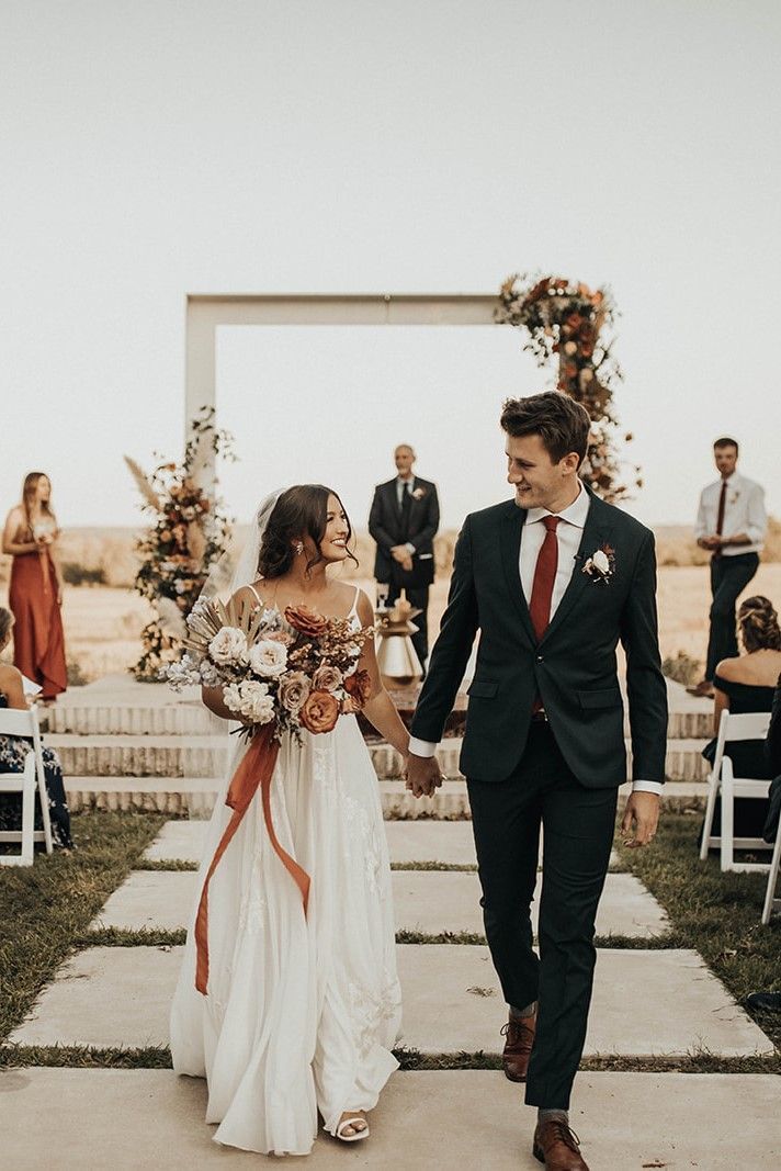 a bride and groom walking down the aisle after their wedding ceremony at an outdoor venue