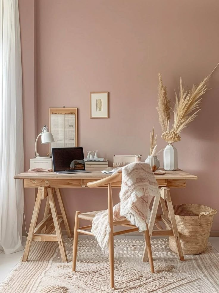 a desk with a laptop on top of it in front of a pink wall and white curtains