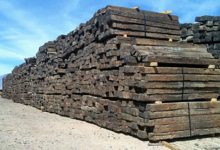 a pile of logs sitting on top of a dirt field next to a blue sky