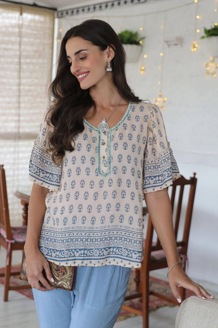 Indian artisan Anchal Ahuja designed this demure top to celebrate the spring season. Crafted from 100% viscose, the short-sleeved blouse features a screen-printed floral motif on an ivory background and embroidery around the neckline. Sequins and bell sleeves with pretty ruffles add a feminine touch to the blouse. Bohemian Half Sleeve Summer Tops, Casual Rayon Blouse With Split Neck, Bohemian Printed Short Sleeve Tops, Bohemian Half Sleeve Blouse For Spring, Bohemian Half Sleeve Relaxed Fit Blouse, Bohemian Half Sleeve Blouse For Vacation, Bohemian Short Sleeve Tops For Spring, Spring Bohemian Half-sleeve Blouse, Relaxed Fit Blouse With Floral Embroidery And Short Sleeves