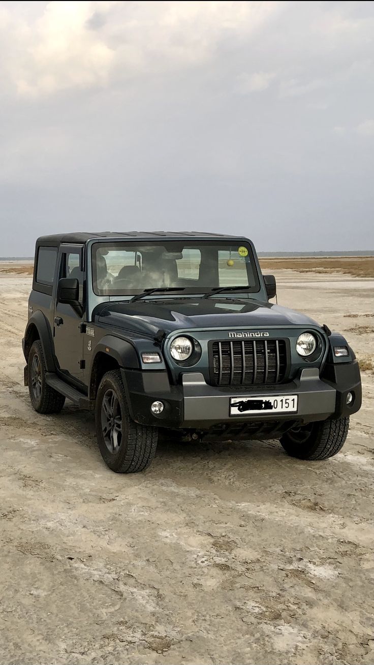 a black jeep is parked in the middle of an empty field with no one around it