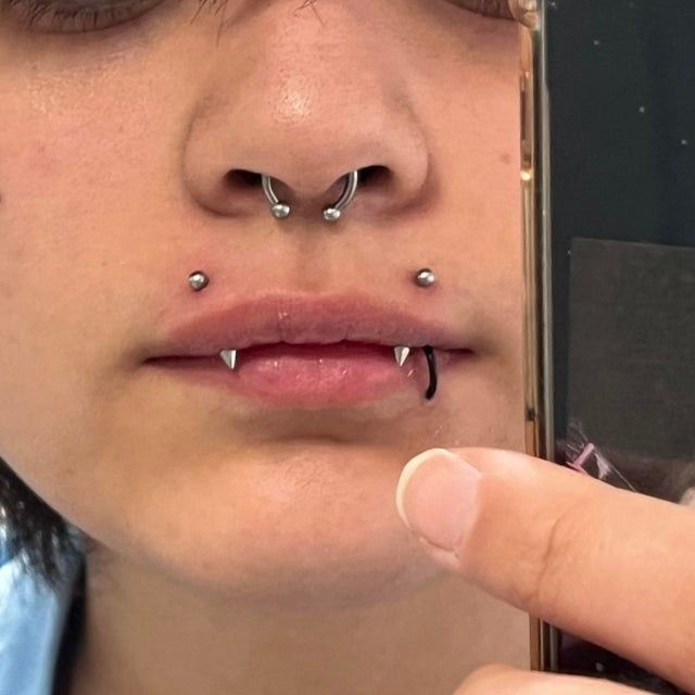 a woman with piercings on her nose holding a cell phone