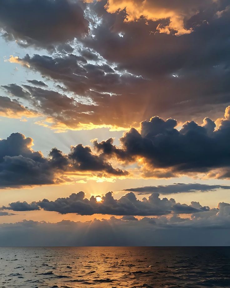 the sun is setting over the ocean with clouds in the sky and on the water