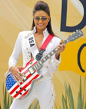 a woman with an american flag guitar in front of a sign that says d is for usa