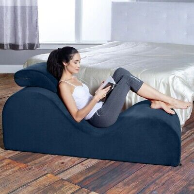 a woman sitting on a bean bag chair reading a book