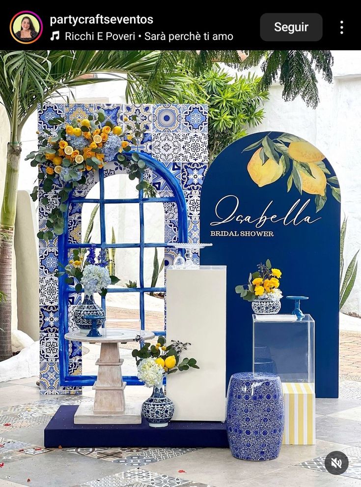 a blue and white display with yellow flowers in vases on the table next to it