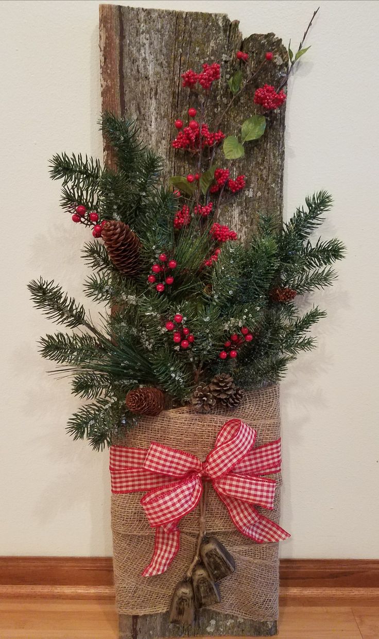 a christmas decoration with pine cones and red berries in a burlocked vase