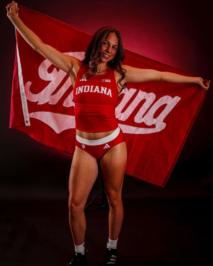 a woman in red shirt and white shorts holding up a flag