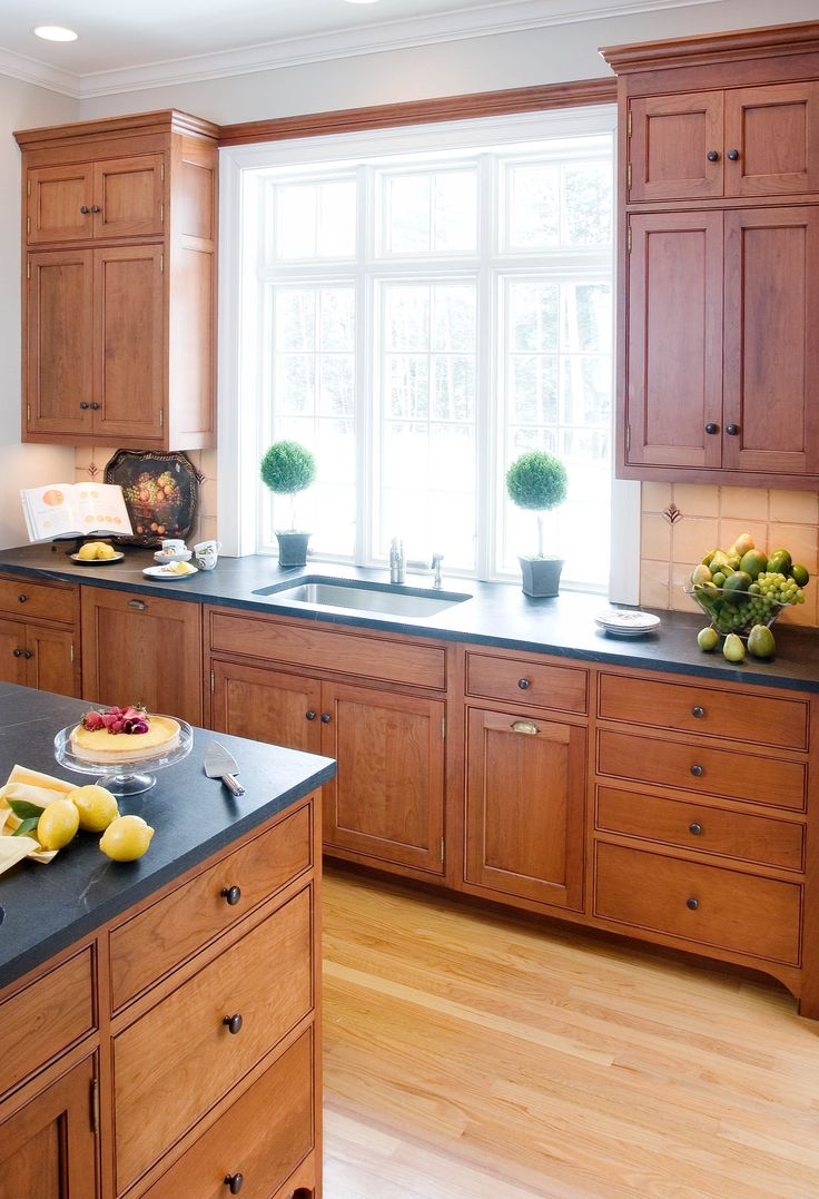 a kitchen filled with lots of wooden cabinets and counter top space next to a window