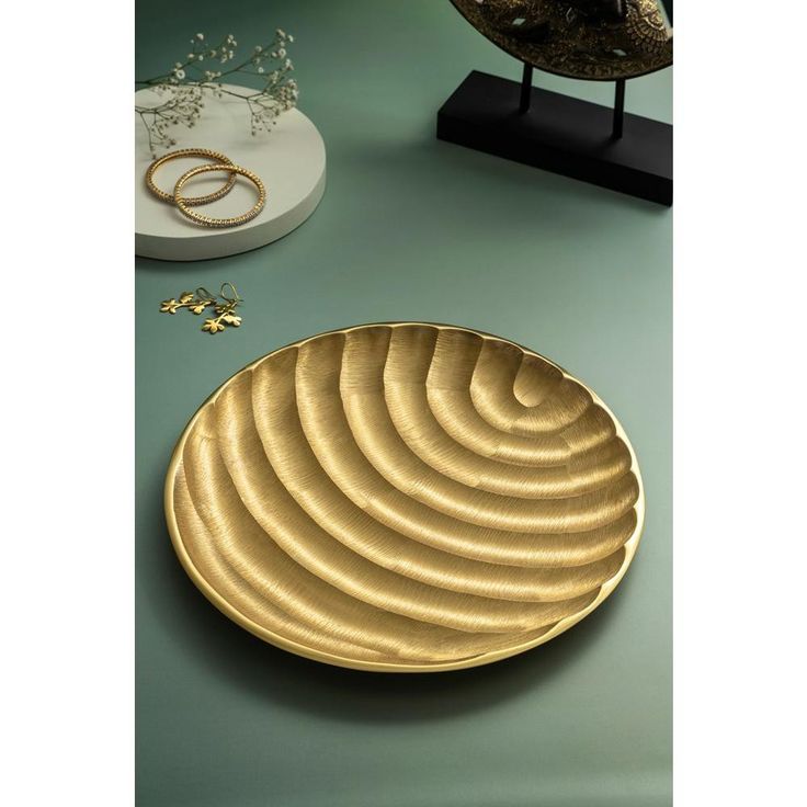 a gold plate sitting on top of a green table next to rings and other accessories