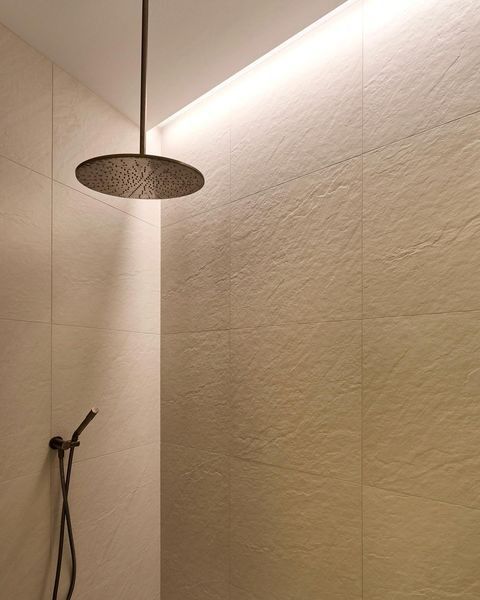 a bathroom with a large shower head next to a white wall