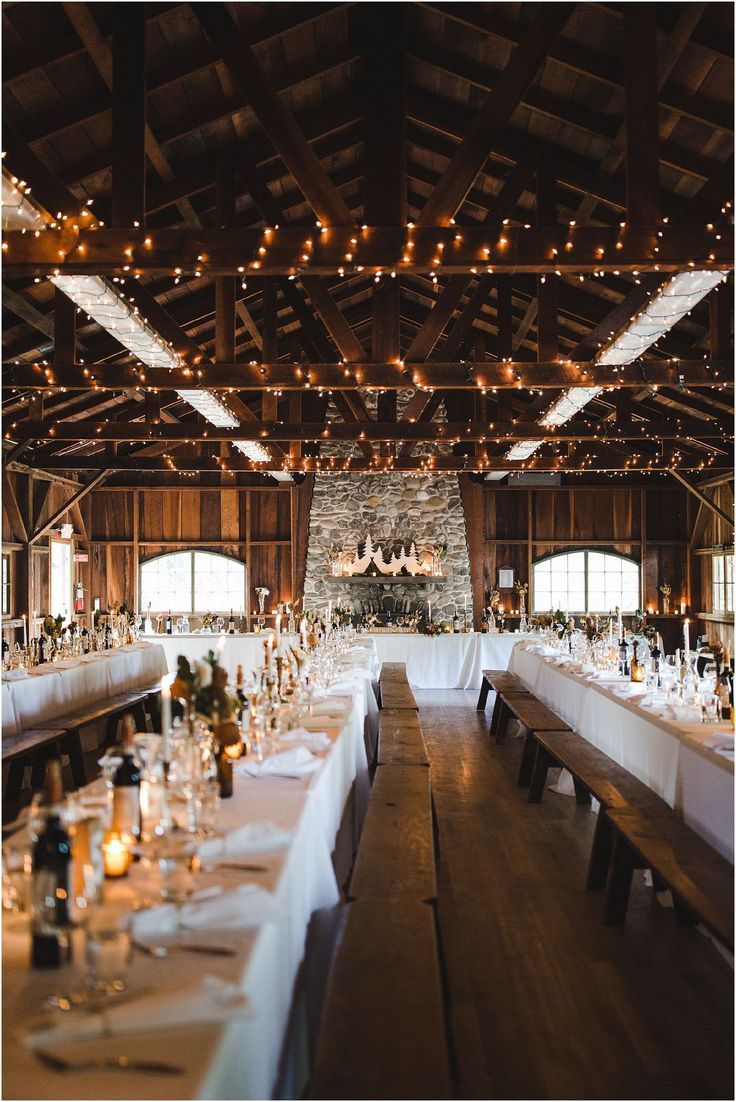 the tables are set up for an event with white linens and lights hanging from the ceiling