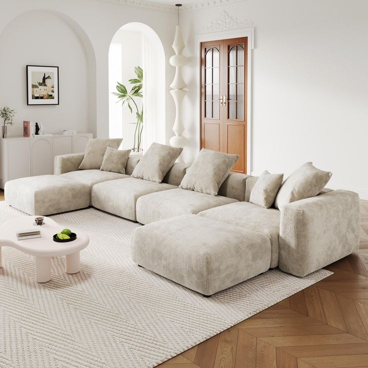 a living room with a large sectional couch and coffee table in the middle, on top of a white rug