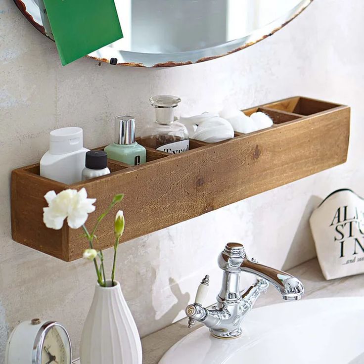 a bathroom sink with a wooden shelf above it and a mirror on the wall behind it