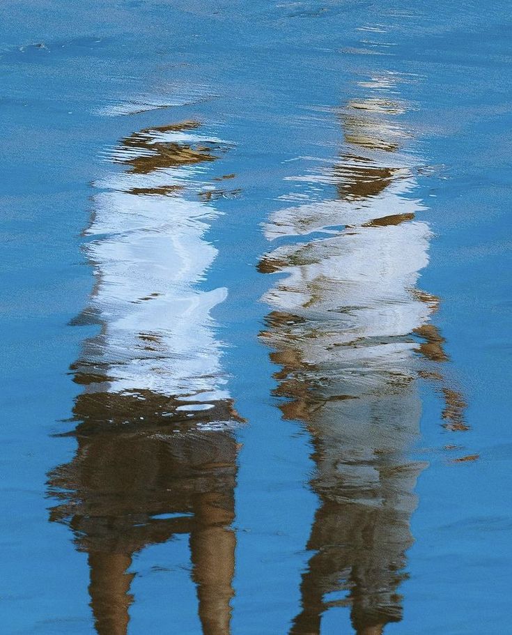 two people are standing in the water with their reflection