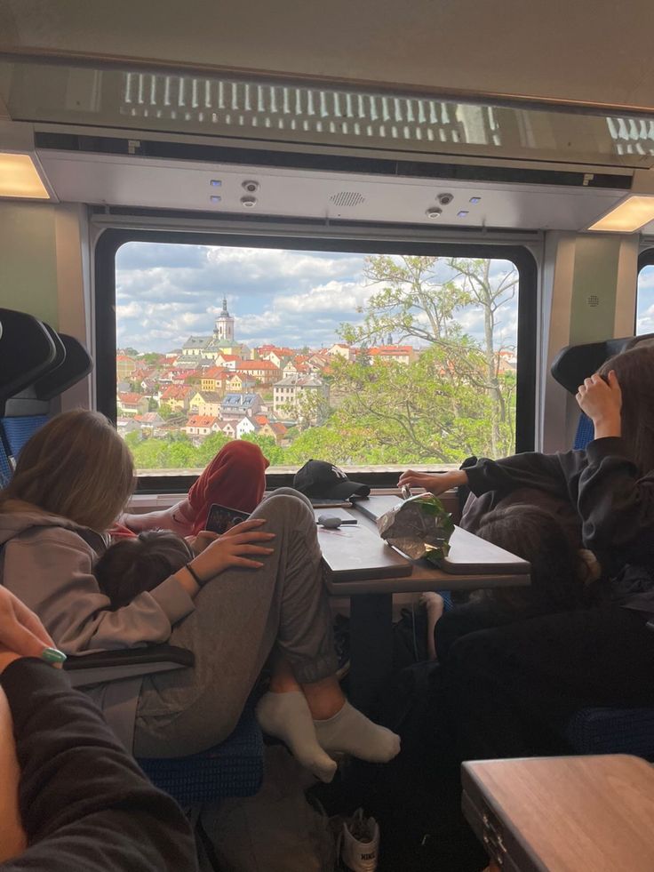 some people are sitting on a train looking out the window