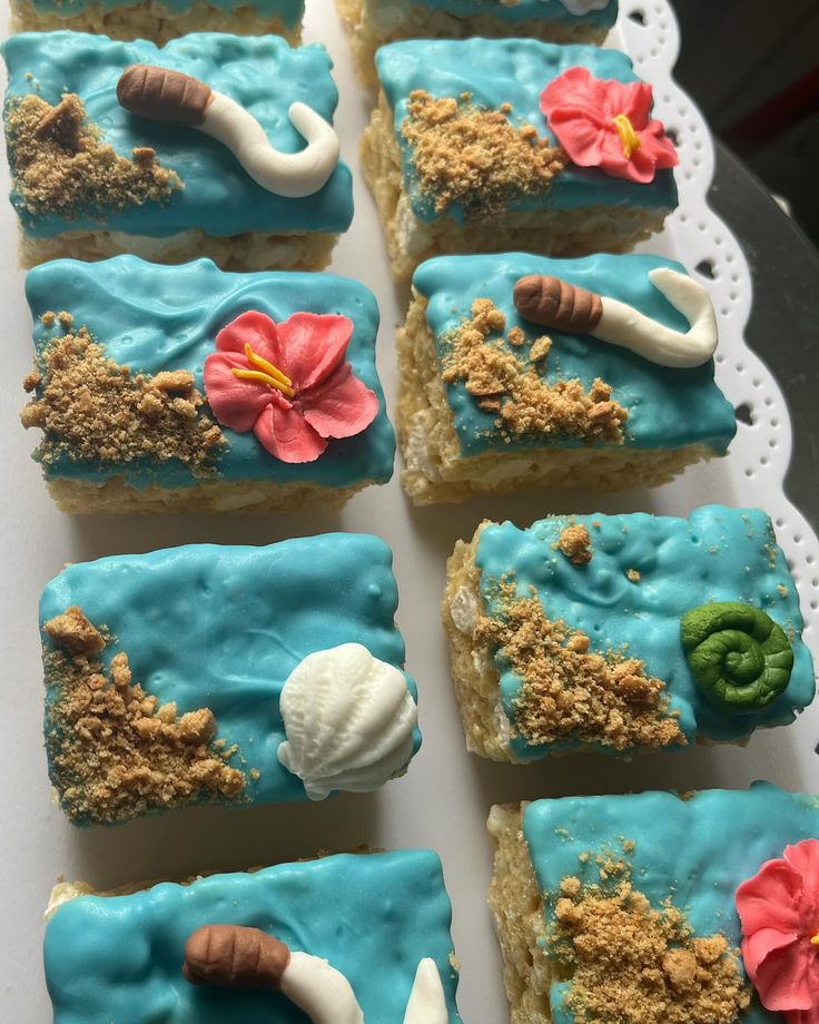 there are many pieces of cake on the tray with blue frosting and shells in it