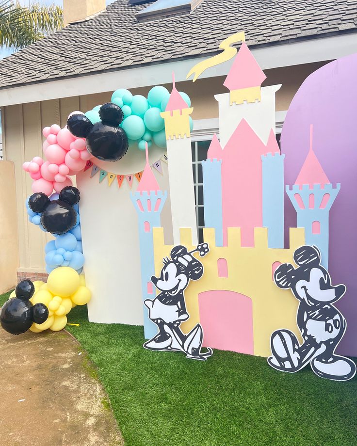 the balloon arch is decorated with mickey mouse and minnie mouse balloons in front of a house