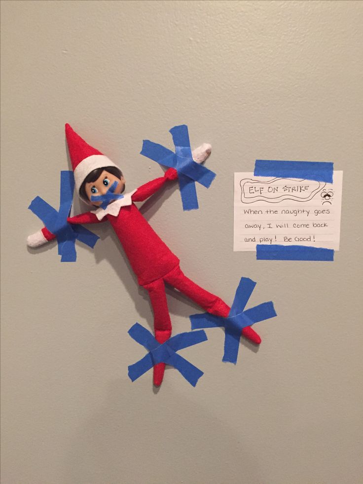 an elf is hanging on the wall with blue streamers and a note attached to it