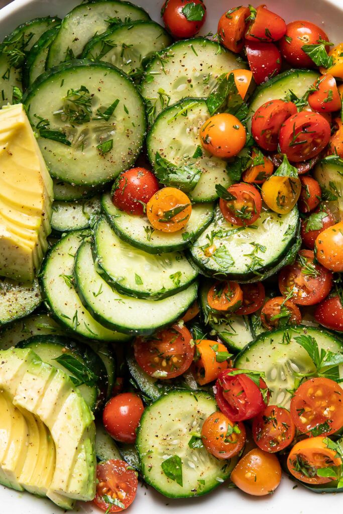 a white bowl filled with cucumbers and tomatoes