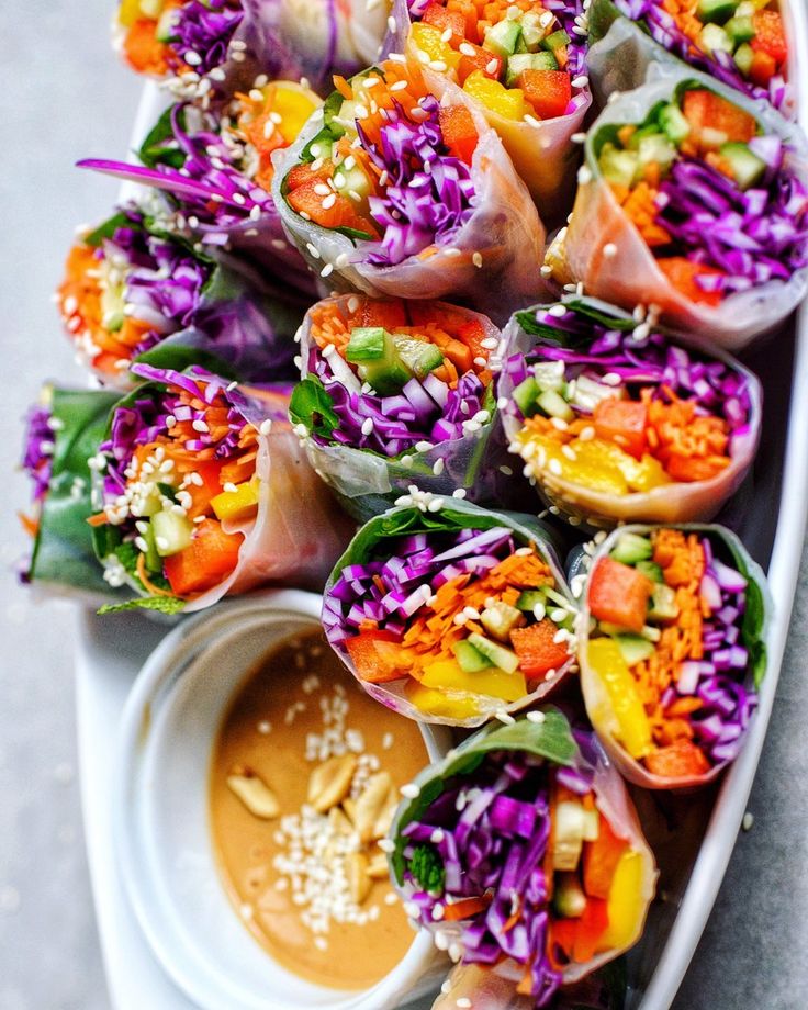 a white plate topped with lots of veggies next to a bowl of dipping sauce